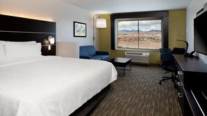 A hotel room with a large bed, a desk, a chair, a TV, and a window with a desert view. - Holiday Inn Express & Suites Bullhead City by IHG (Bullhead City)