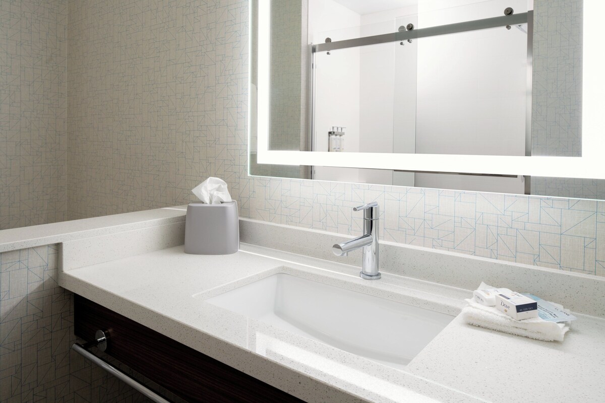A modern bathroom with a large mirror, a sink, and a towel rack.