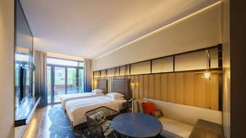 A hotel room with a large bed, a sofa, a small table, and a TV.