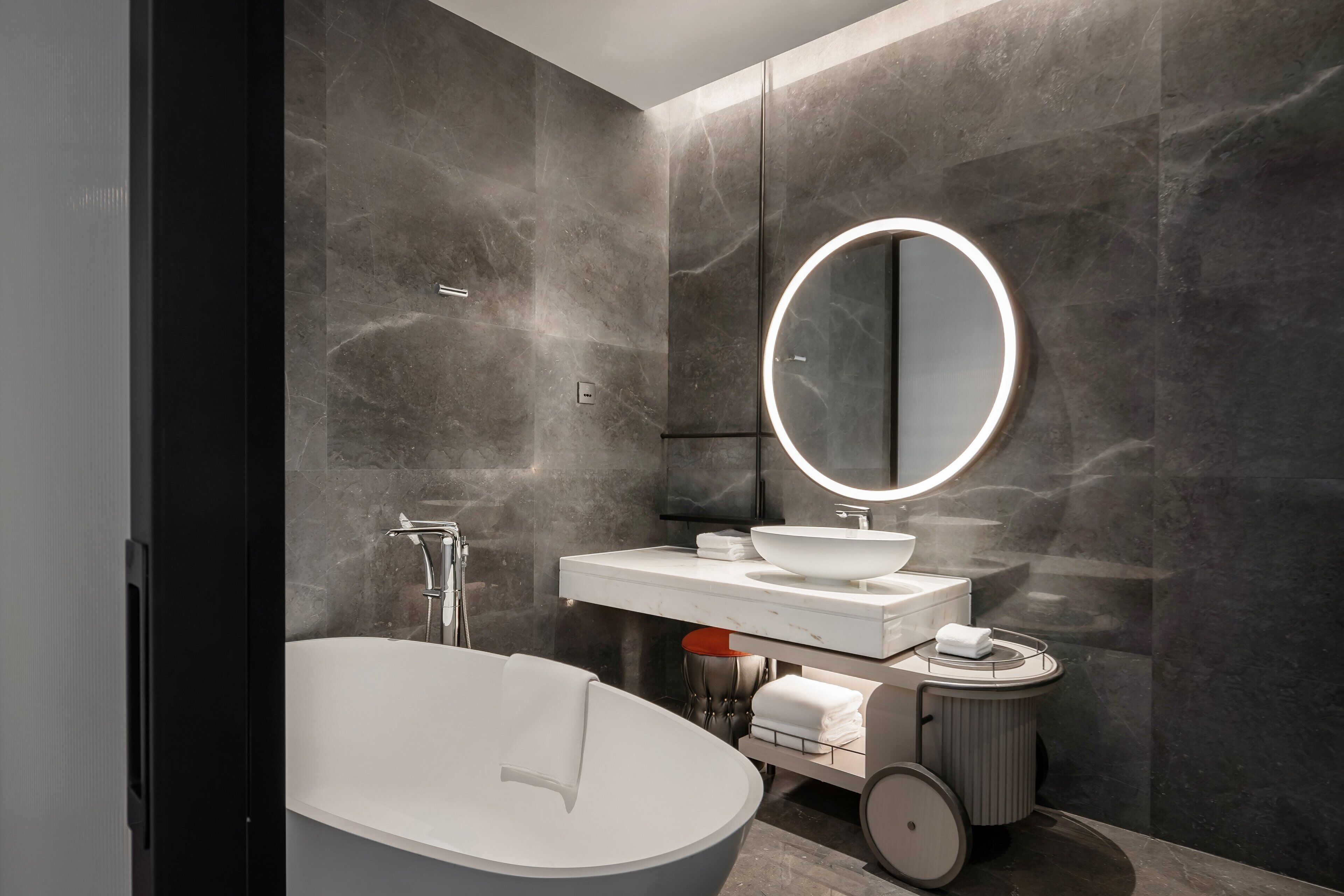 A modern bathroom with a freestanding bathtub, a round mirror, and a white vanity with a sink.