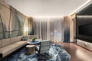 A modern living room with a sofa, a round coffee table, a side table, and a TV. - Hotel Indigo Nanjing Garden Expo by IHG (Nanjing)