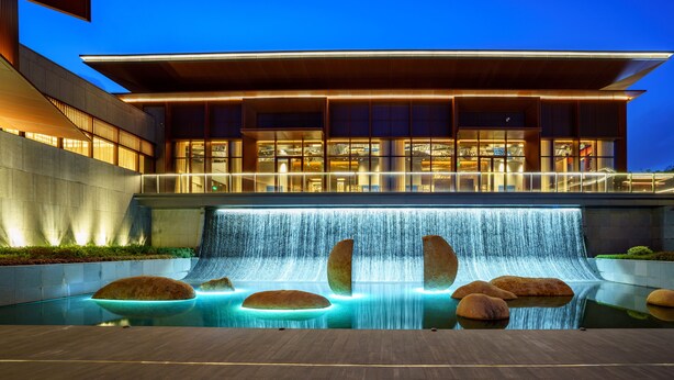 Un edificio moderno con una cascada y una piscina con rocas.