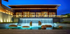 Un bâtiment moderne agrémenté d’une cascade et d’une piscine avec des rochers.