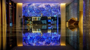 A modern lobby with a reflective floor, a geometric wall design, and a reception desk. - Hotel Indigo Nanjing Garden Expo by IHG (Nanjing)