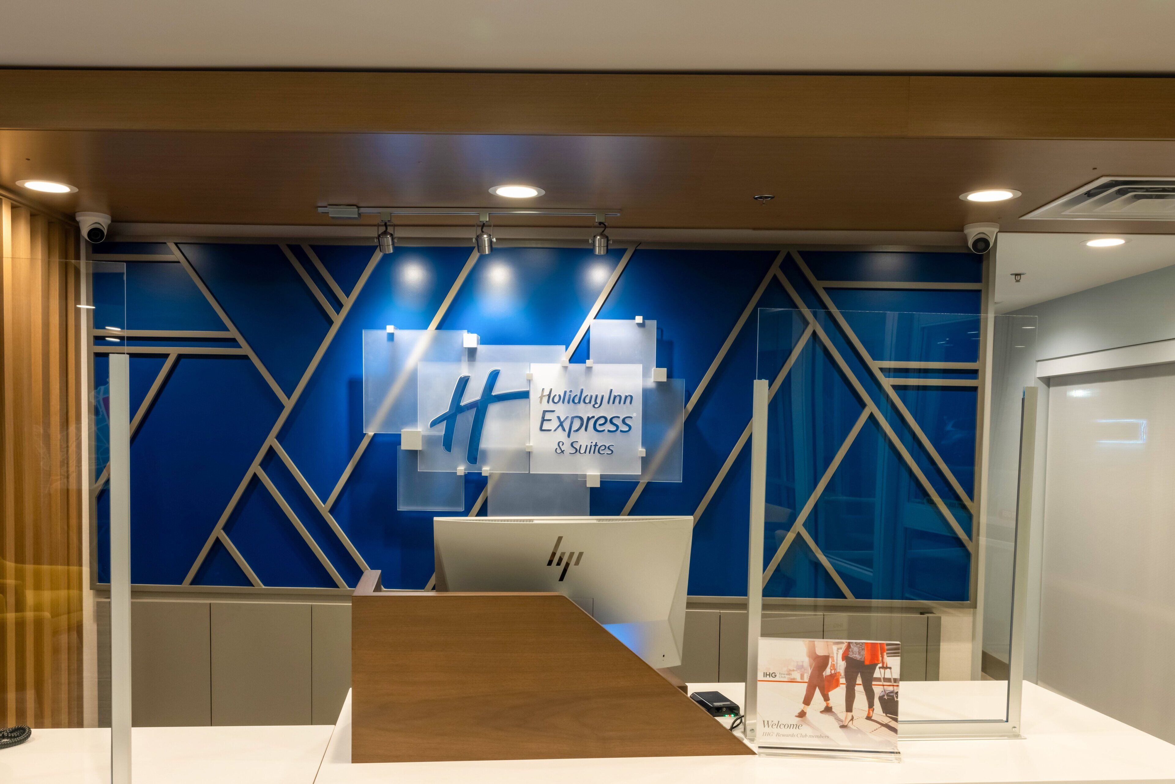 Een receptiebalie met blauw-witte kleuren, een bord met Holiday Inn Express & Suites erop en een computerscherm.