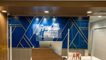Een receptiebalie met blauw-witte kleuren, een bord met Holiday Inn Express & Suites erop en een computerscherm.