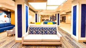 A hotel lobby with a sofa, chairs, and a large wall map. - Holiday Inn Express & Suites Harrisonburg University Area by IHG (Harrisonburg)