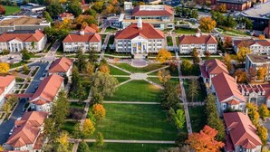 An aerial view of a campus with multiple buildings, a central lawn, and surrounding trees. - Holiday Inn Express & Suites Harrisonburg University Area by IHG (Harrisonburg)
