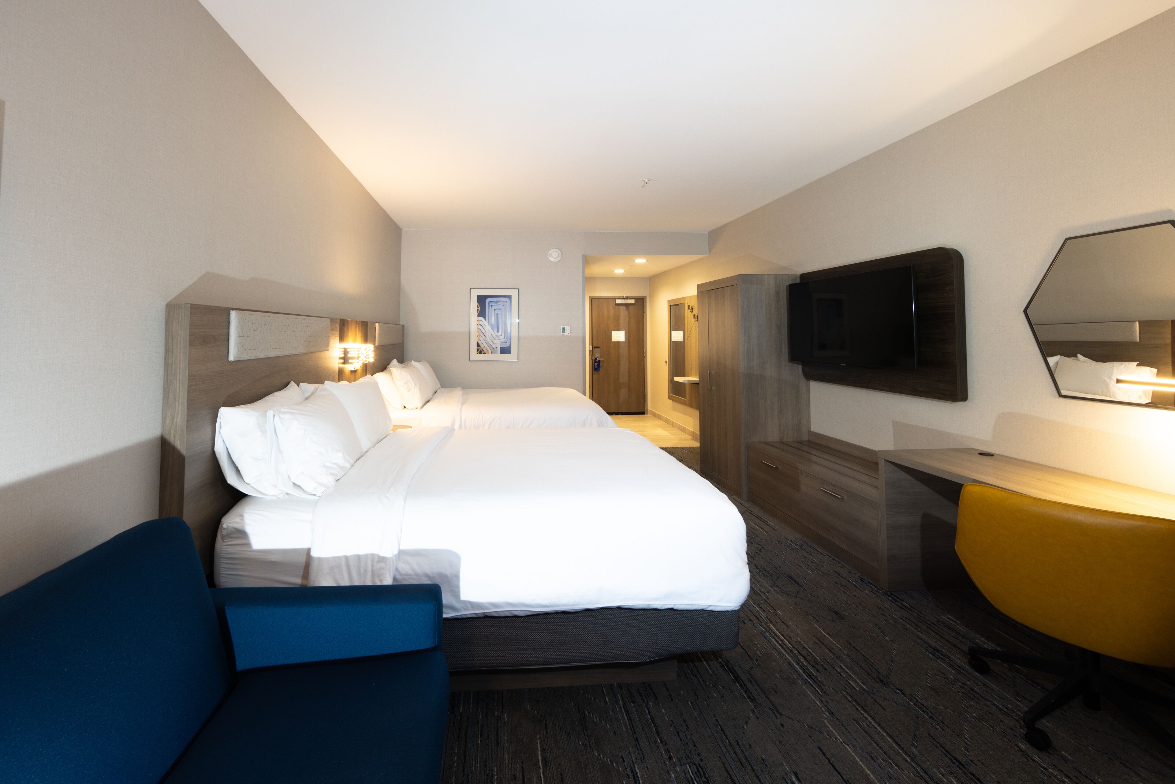 Een hotelkamer met een groot bed, een bureau, een stoel, een televisie en een spiegel.