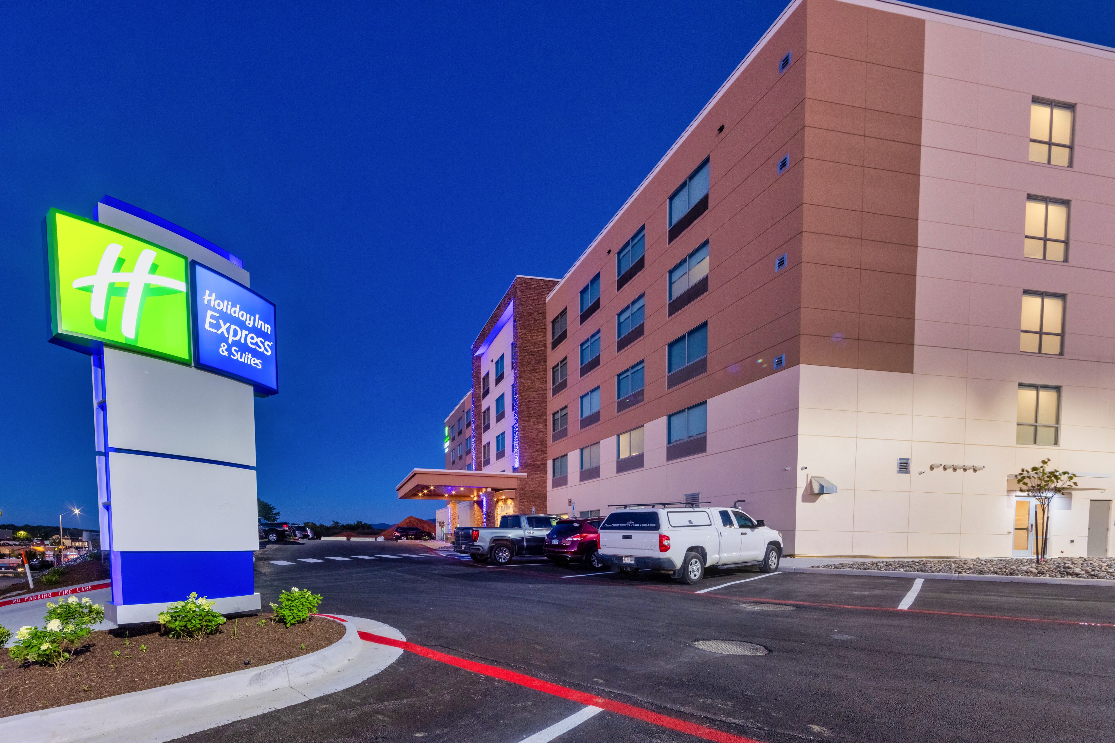 Un bâtiment de l’hôtel Holiday Inn Express & Suites, avec un parking et une enseigne.