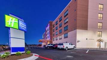 Un bâtiment de l’hôtel Holiday Inn Express & Suites, avec un parking et une enseigne.