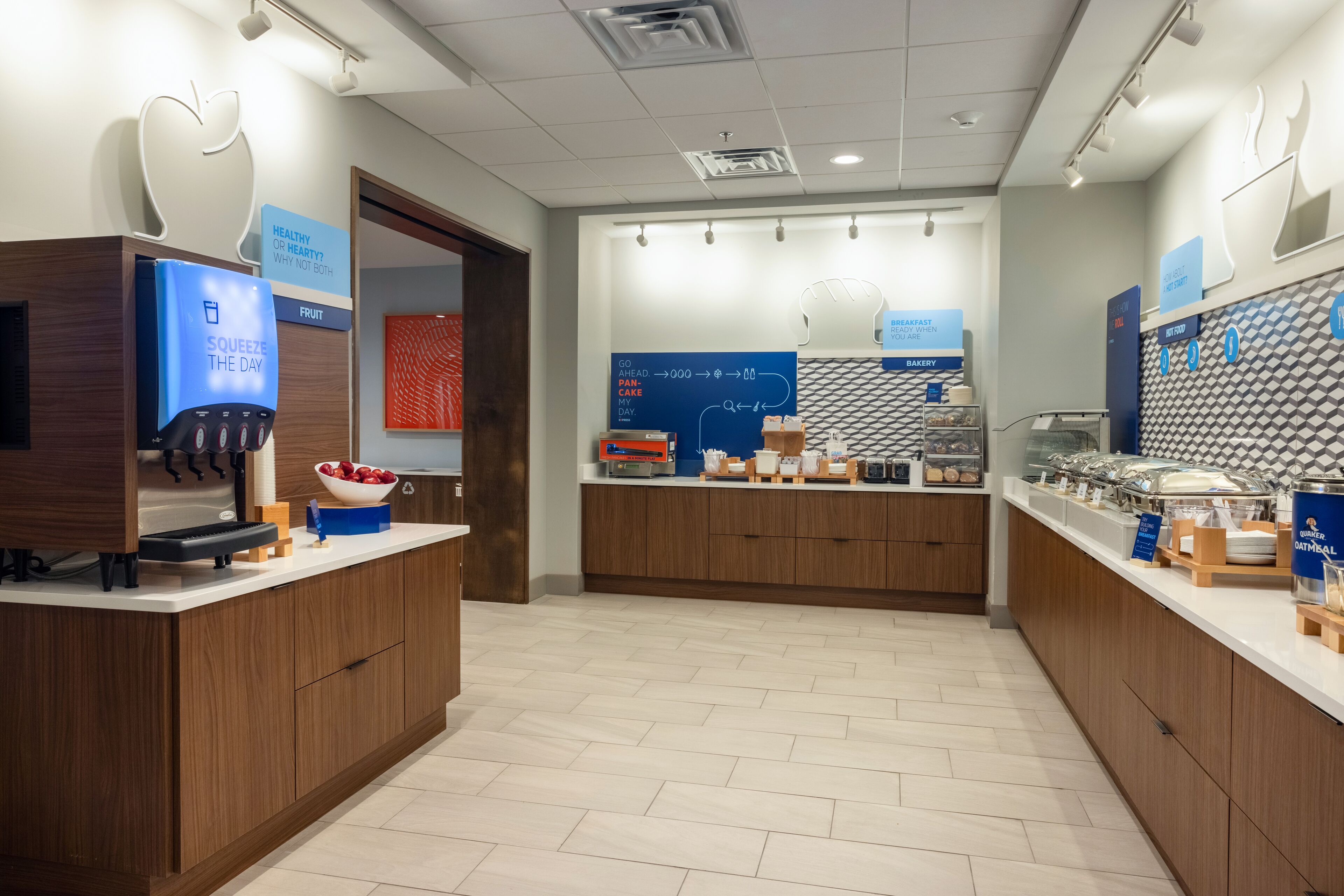 A modern breakfast area with a fruit dispenser, a digital scale, and a variety of breakfast items on display.