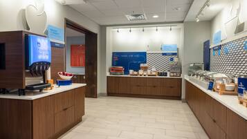 A modern breakfast area with a fruit dispenser, a digital scale, and a variety of breakfast items on display.