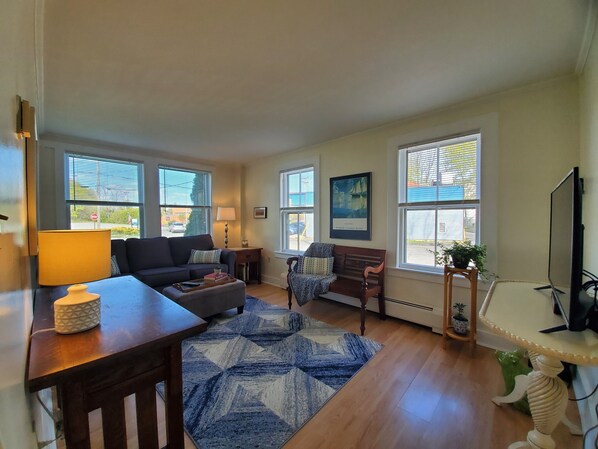 A living room with a sofa, a coffee table, a rug, a bench, and a TV.