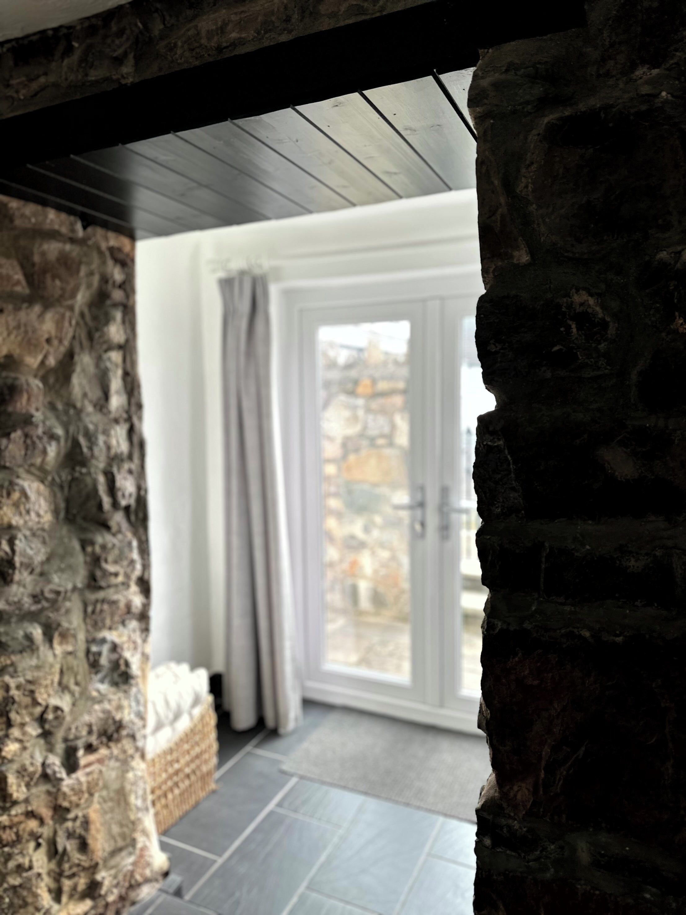 A stone wall with a view of a room through a window.