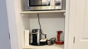 A kitchen with a built-in microwave, coffee maker, and storage shelves. - A Small Hotel Room for Mountain Lovers (Canmore)