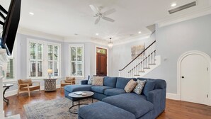 Ein Wohnzimmer mit einem Ecksofa, einem runden Couchtisch und einer Deckenleuchte.