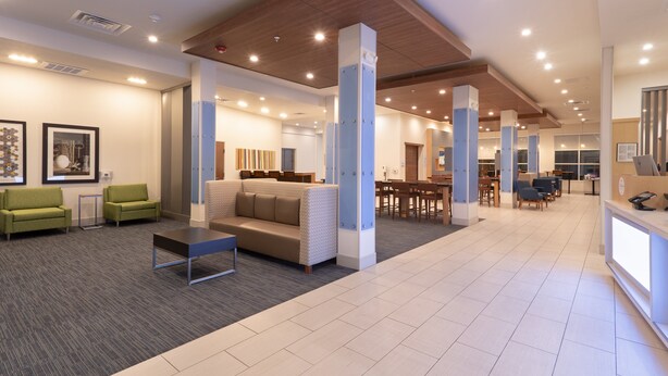 Un hall d’entrée moderne avec un canapé, des fauteuils, une table basse et un comptoir de réception.