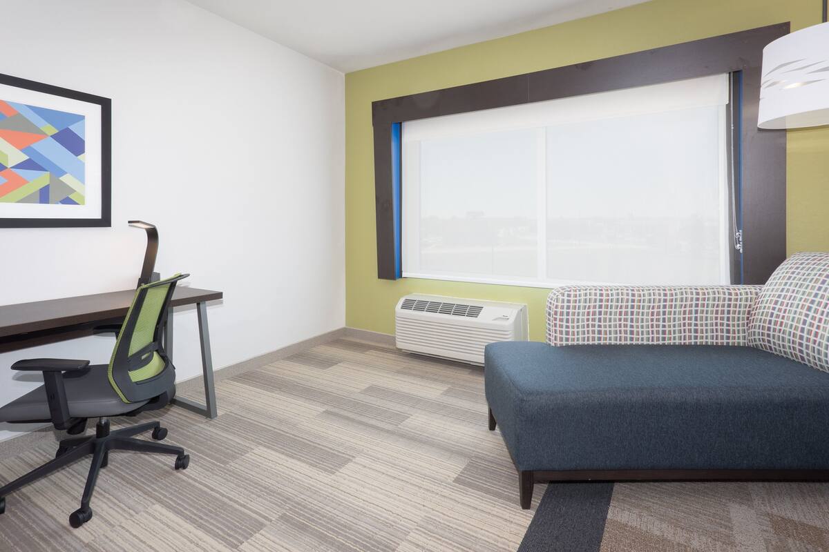 A room with a desk, office chair, and a sofa.