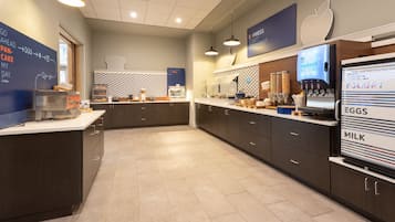 A modern kitchen with dark cabinetry, a large island, and a digital menu display.