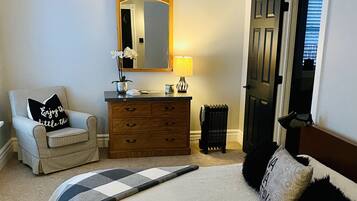 Un dormitorio con cama, una silla, cómoda, espejo y puerta.