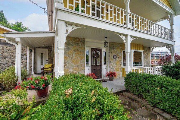 A two-story house with a porch, stone walls, and a number '53' sign.