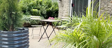 Une terrasse avec un parasol rouge, une table en bois et des plantes en pot.