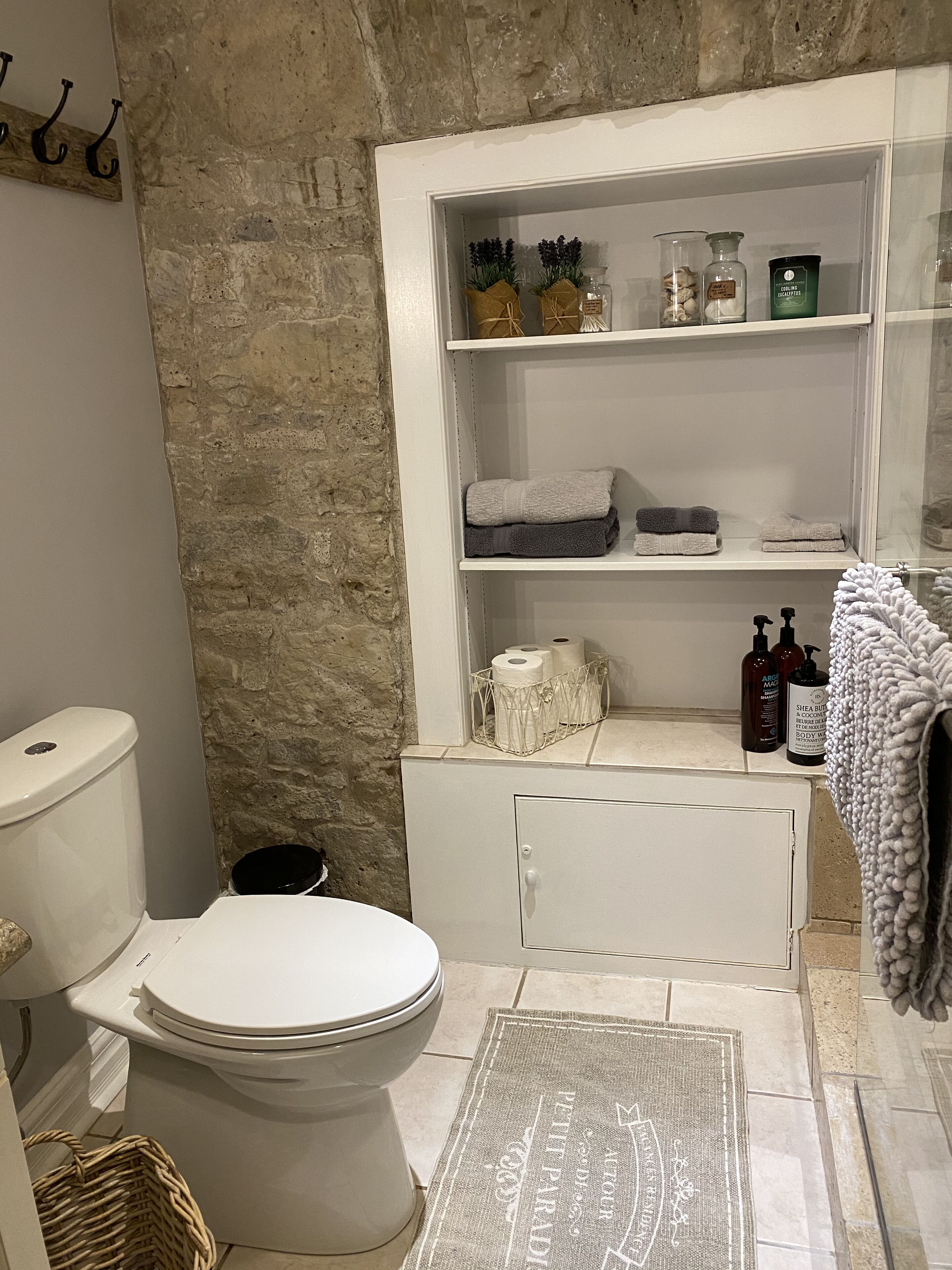 A bathroom with a toilet, a shelf with toiletries, and a towel rack.