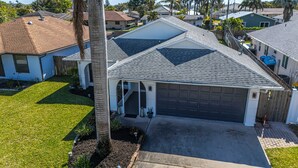 A residential house with a garage, a covered driveway, and a well-maintained lawn.