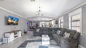 A modern living room with a sectional sofa, a coffee table, and a large flat-screen TV.
