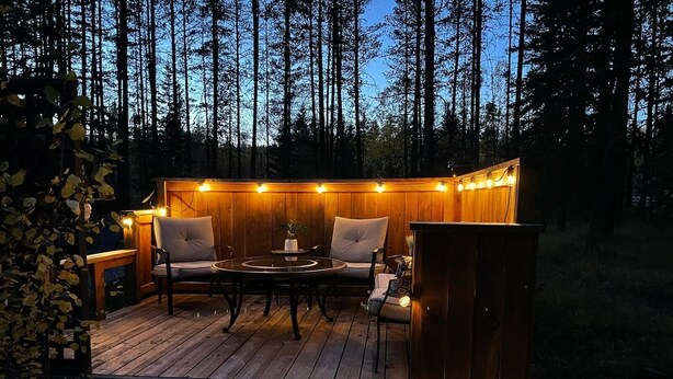 Ulkoterassi, jossa on pyöreä pöytä ja tuoleja, ja jonka ympärillä on valonauhoja.