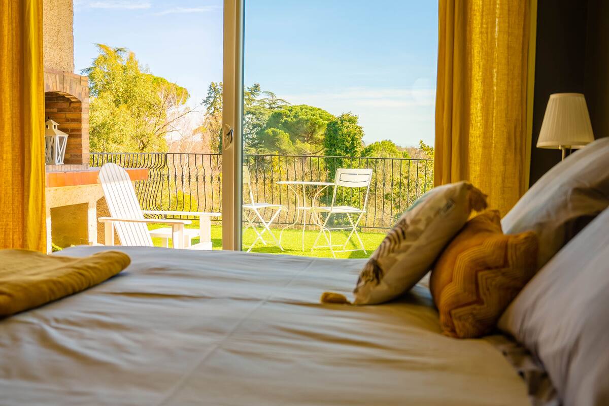 Ein Hotelzimmer mit Bett, Blick auf die Terrasse und einem Tisch mit Stühlen.