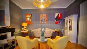 A living room with a fireplace, two yellow armchairs, a round coffee table, and a modern pendant light. - Le Rez de Jardin Albi (Albi)