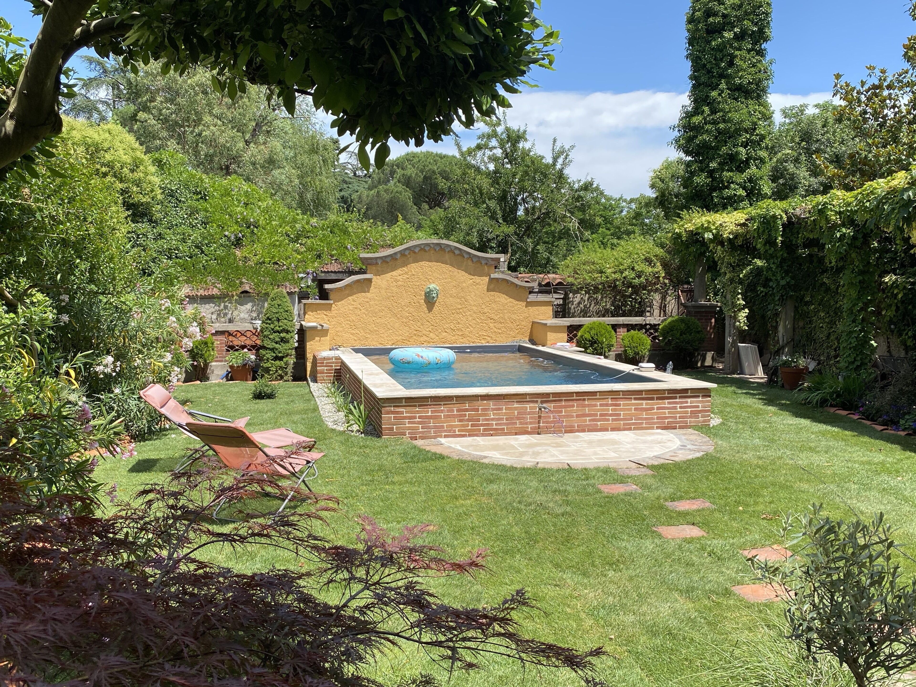 Un patio trasero con piscina, patio de ladrillo y césped.