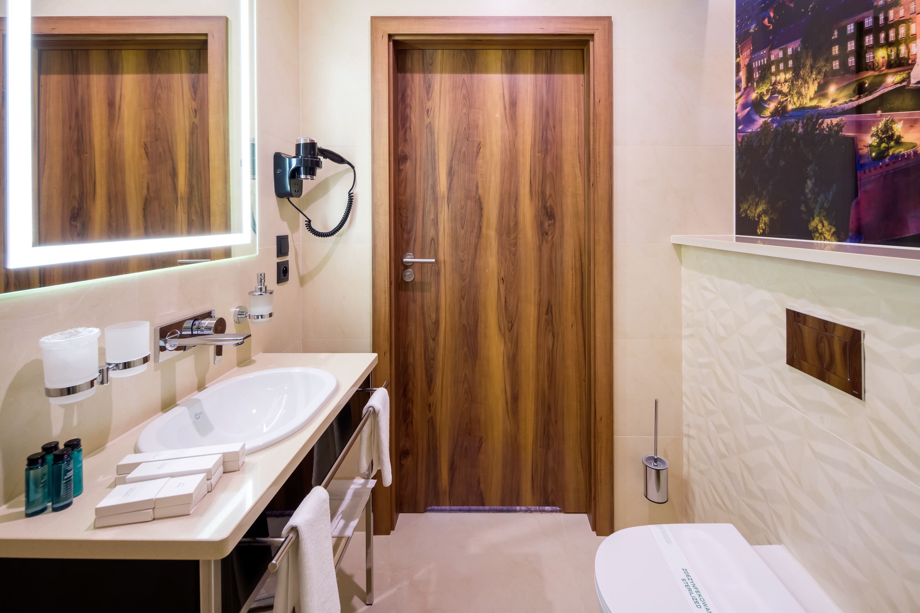 A modern bathroom with wooden doors, a large mirror, dual sinks, and a toilet.