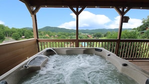 Un jacuzzi en una terraza de madera con vistas a un paisaje montañoso.
