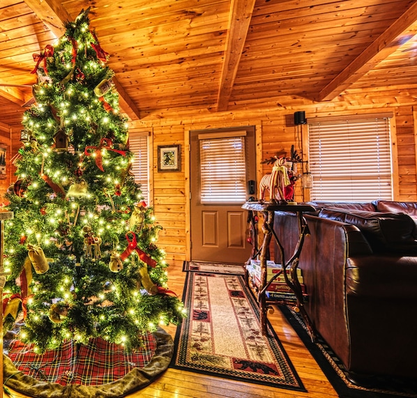 L’intérieur chaleureux d’un chalet, avec un sapin de Noël décoré, des murs en bois, un canapé en cuir et un plafond en bois rustique.
