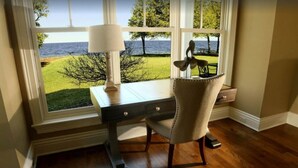 Un bureau avec une lampe et une chaise, placé devant une fenêtre donnant sur la mer.