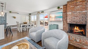 Una sala de estar acogedora con chimenea, un comedor con vistas a la playa y una cocina con alacenas blancas.