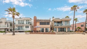 Una propiedad frente a la playa con casas modernas, una playa de arena y palmeras.