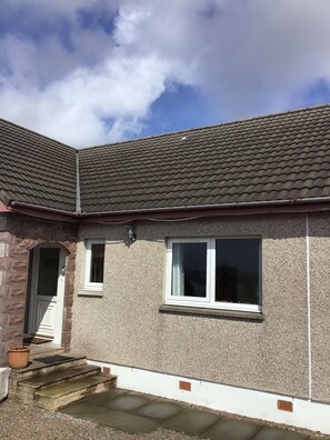 A house with a tiled roof, a front door, and a small window.