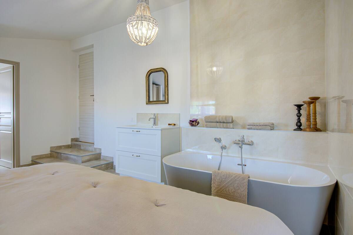 A modern bathroom with a bathtub, a vanity, and a mirror.