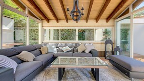 A modern living room with a glass coffee table, a grey sofa, and a wooden ceiling. - Domaine Le Courti (Le Barcares)