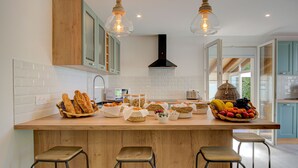 A kitchen with a wooden island, bar stools, and various food items displayed on the counter. - Domaine Le Courti (Le Barcares)