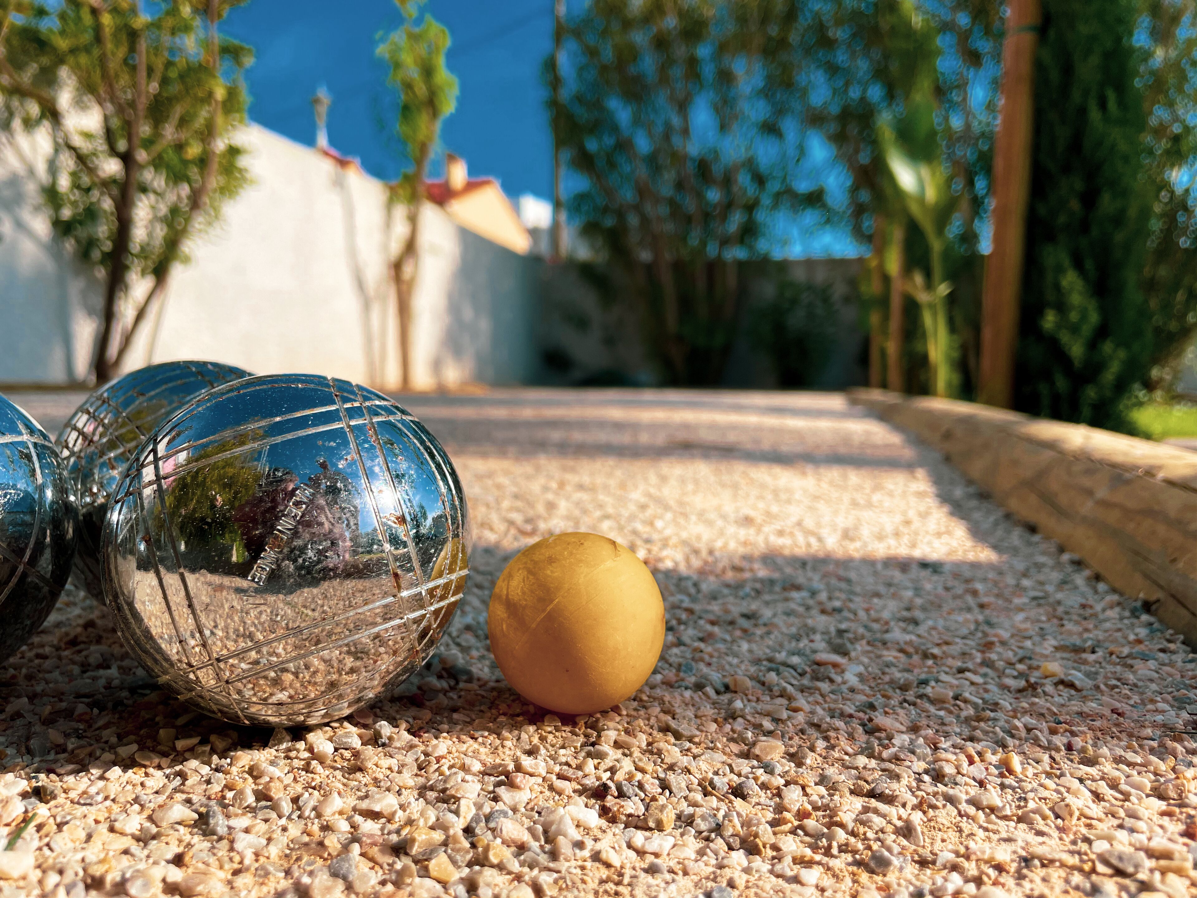 Three metallic spheres on a gravel surface with a single yellow sphere beside them.