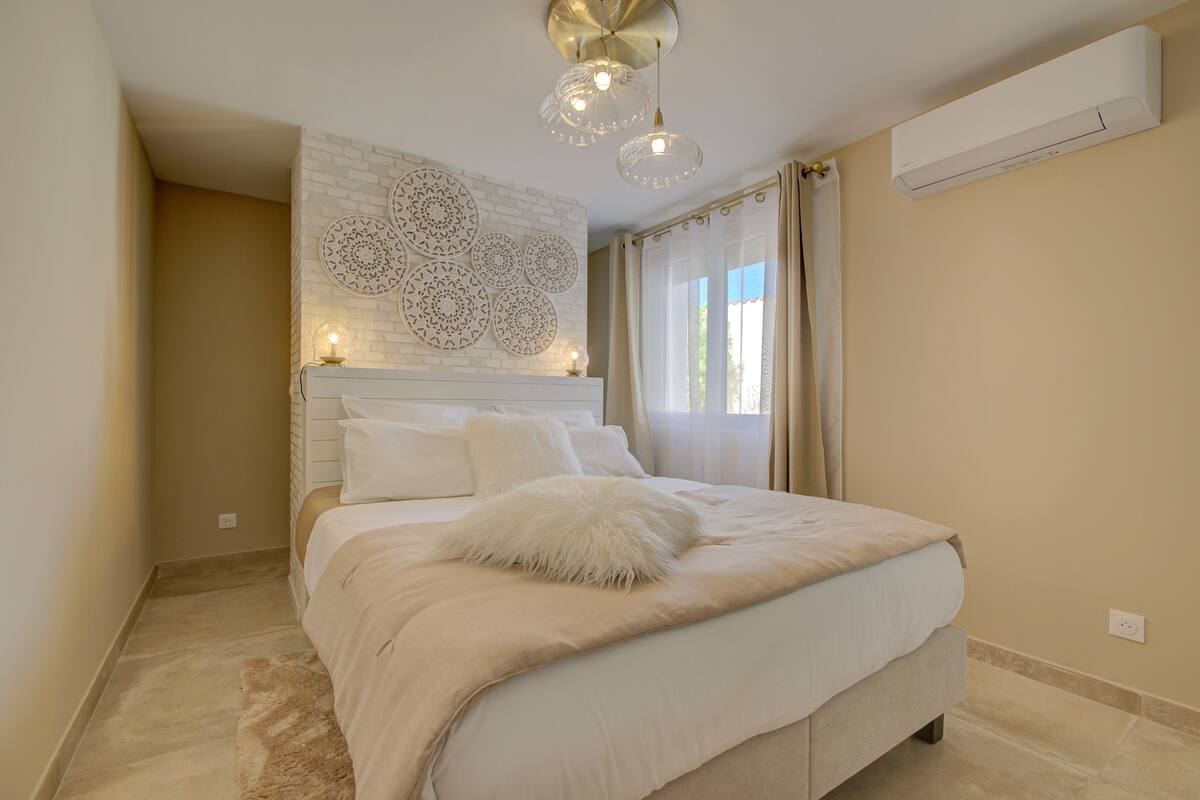 A bedroom with a large bed, a decorative wall, and a ceiling light fixture.