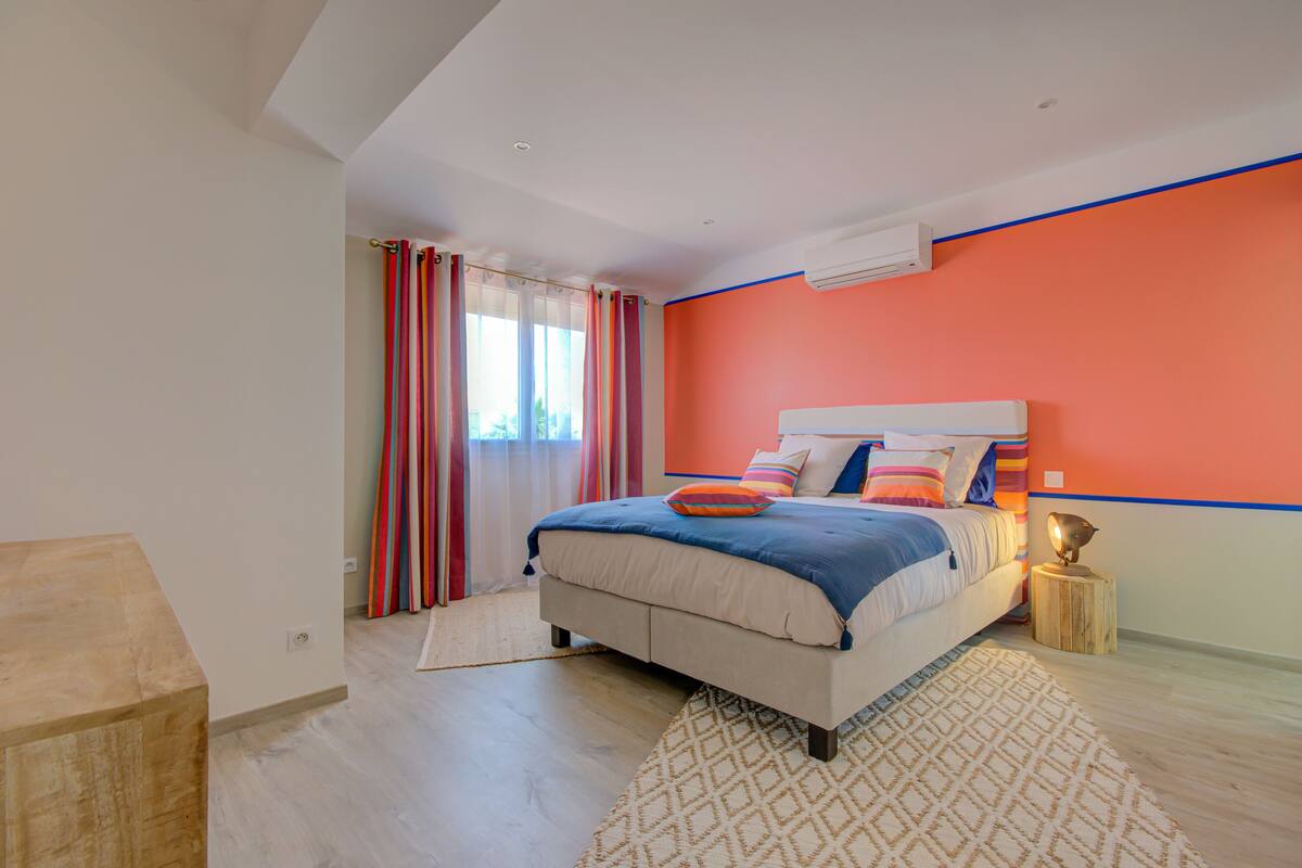 A bedroom with a bed, curtains, a rug, and a nightstand.