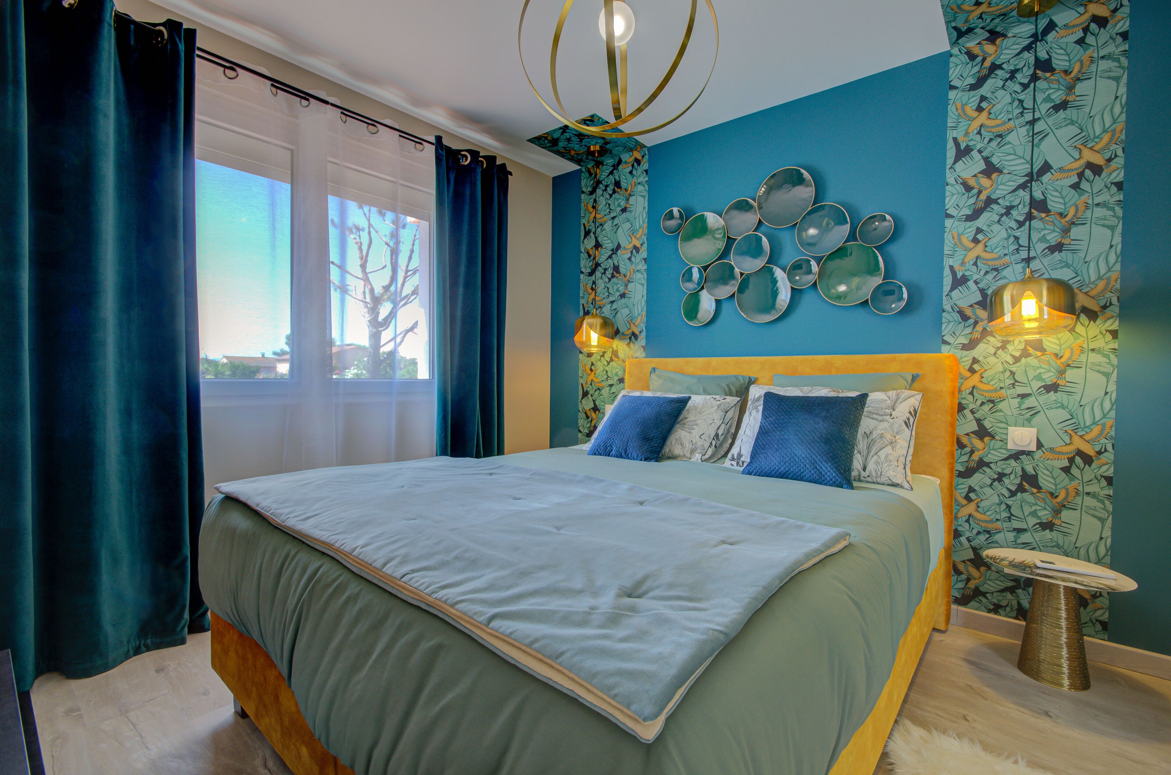 A bedroom with a bed, curtains, a wall with decorative plates, and a small table.