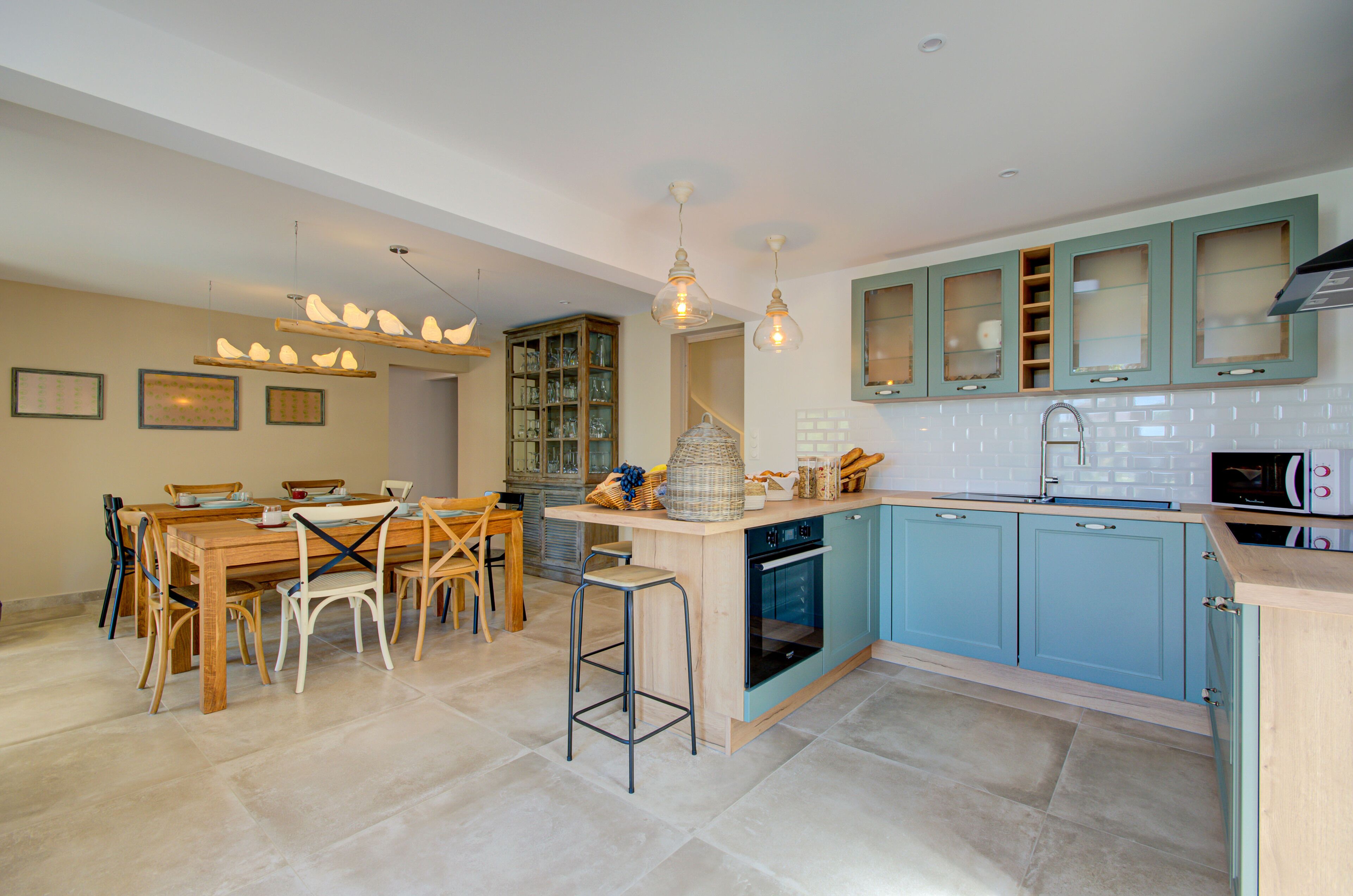 Una cocina moderna con una mesa de comedor de madera, armarios azules y una isla central con taburetes.