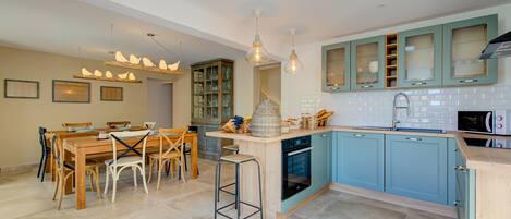 Una cocina moderna con una mesa de comedor de madera, armarios azules y una isla central con taburetes.